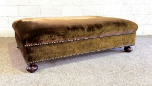 A large greeny brown 'velvet' covered ottoman, with cushioned top and nailed sides, on bun feet,