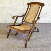 A Colonial reclining caned armchair, folding and with scrolled armrest and bentwood legs