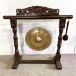 A Chinese style hall / dinner gong, the circular brass gong suspended from a carved and turned