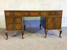 A George III style mahogany veneered kneehole desk, with inset leathered top and seven drawers (