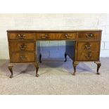 A George III style mahogany veneered kneehole desk, with inset leathered top and seven drawers (