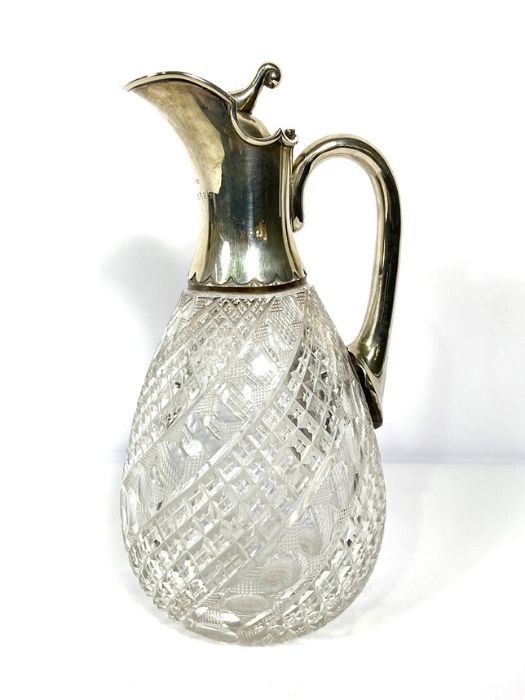 A silver mounted claret jug, hallmarked Birmingham 1919, with a pouring spout, hinged lid and scroll