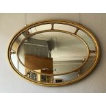 A Regency style oval sectional composition gilt wall mirror, with a central oval plate and a