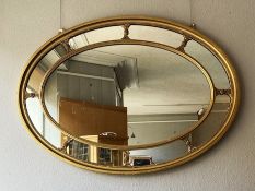 A Regency style oval sectional composition gilt wall mirror, with a central oval plate and a