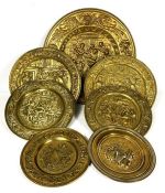 Seven assorted pressed brass alms style plaques, various sizes, embossed width figures and