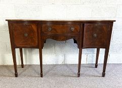 A George III style mahogany sideboard, late 19th century, with serpentine top and a central frieze