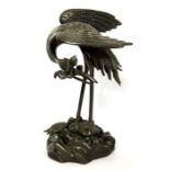 A Japanese bronze figure of a crane, Meiji Period style, modelled with head bowed and holding a