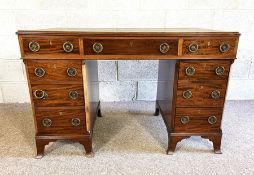 A George III style small kneehole desk, with leathered top, over arrangement of nine drawers
