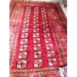 A modern Bokhara style rug, with three lines of ‘elephant foot’ medallions, within guard stripes,