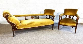 An Edwardian chaise longue, and matching armchair, with pierced fretwork and padded backs, currently