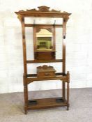 An Edwardian oak hall stand, circa 1910, with mirrored back and six hooks, over a central drawer and