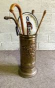 A brass embossed walking stick stand, together with associated canes, including a gnarled wood