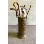 A brass embossed walking stick stand, together with associated canes, including a gnarled wood