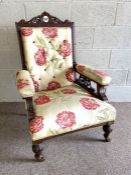 A late Victorian easy chair, with carved back and padded armrests, currently upholstered in floral