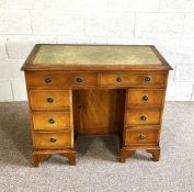 A Georgian style kneehole desk, with green leathered top, over arrangement of drawers and a niche