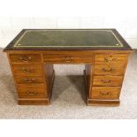 A George III style kneehole desk, circa 1900, with a green leathered top over an arrangement of nine