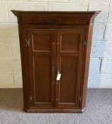 A George III style oak corner cabinet, late 19th century, with two panelled doors and canted