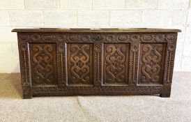 An oak coffer, 17th century, with panelled top and sides, a hinged lid, the front with a carved