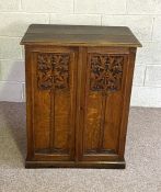 A small oak Arts & Crafts side cabinet, with tow cabinet doors, each carved with a tall foliated '