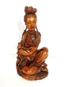 An Asian carved hardwood figure of Guanyin, early 20th century, she seated and holding a lotus