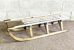 A vintage sledge; together with a decorative wall mirror with panelled back (2)