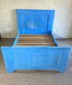 Blue double bed made up of eclectic pieces of wood, apparently collected from Portobello road
