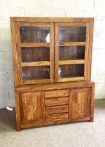 A contemporary hardwood, possibly teak, display cabinet, with two glazed cabinet doors over a base