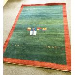A late 20th century decorative rug, with figures on a green field, with red border, possibly