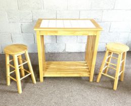 A modern kitchen breakfast table, with two matching stools, the top inset with white tiles, 90cm