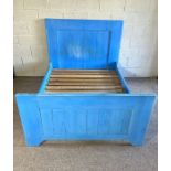 Blue double bed made up of eclectic pieces of wood, apparently collected from Portobello road
