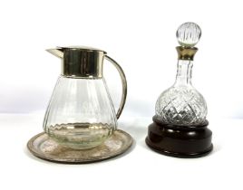 A round bottomed port decanter with wooden stand; also a large clear glass and plated jug and a