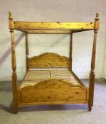 A modern pine four poster bed, with four tapered turned bed posts, supporting a top rail with