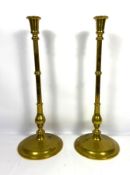A pair of tall vintage brass candlesticks, each with a knopped baluster stem and spreading