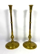 A pair of tall vintage brass candlesticks, each with a knopped baluster stem and spreading