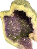 A large natural amethyst geode section, cut and opened for display, with deep internal crevice and