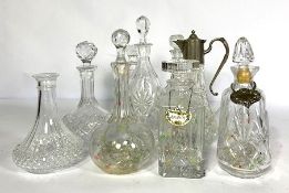 A group of assorted clear glass decanters, including two flat bottomed ships decanters, a silver