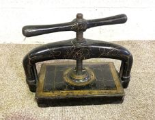 A vintage black and gilt cast iron and brass book press, circa 1900, with screw down press and