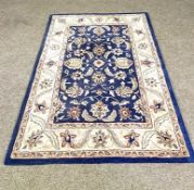 A modern small decorative rug, with blue field and cream border decorated with flowers; and a