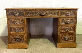 A late Victorian oak desk, with rectangular leathered top, and arrangement of nine drawers, each