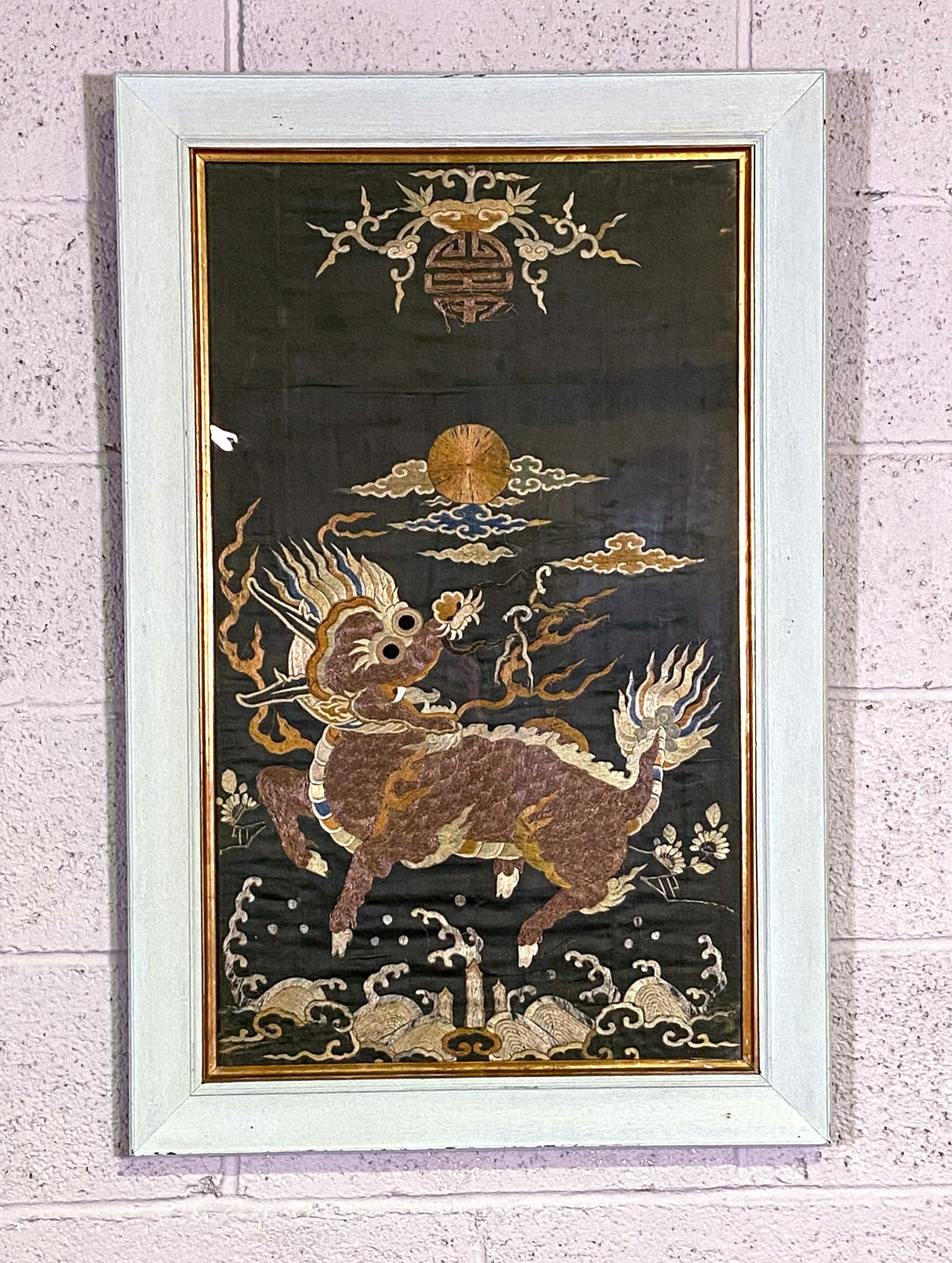 A Chinese silk and embroidered panel, decorated with a Qilin (A mythological beast), with sun above,