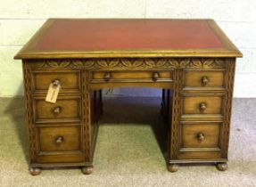 A vintage Jacobean style oak desk, 20th century, with red leathered top, over arrangement of