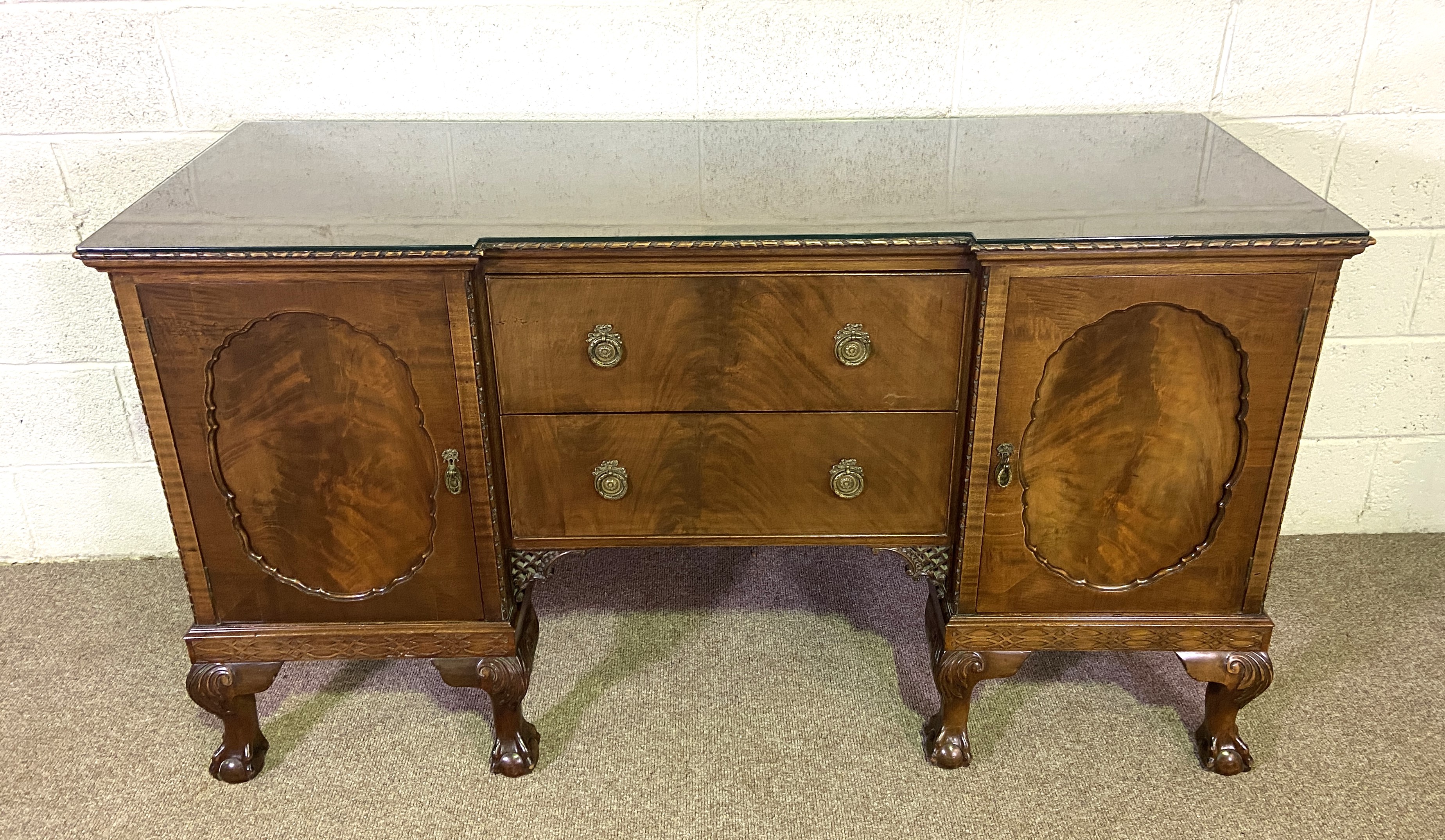 A George III style breakfront mahogany veneered sideboard, the plain top with a moulded edge, over