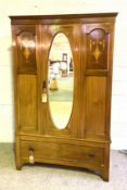 An Edwardian mahogany single door wardrobe with oval mirrored door