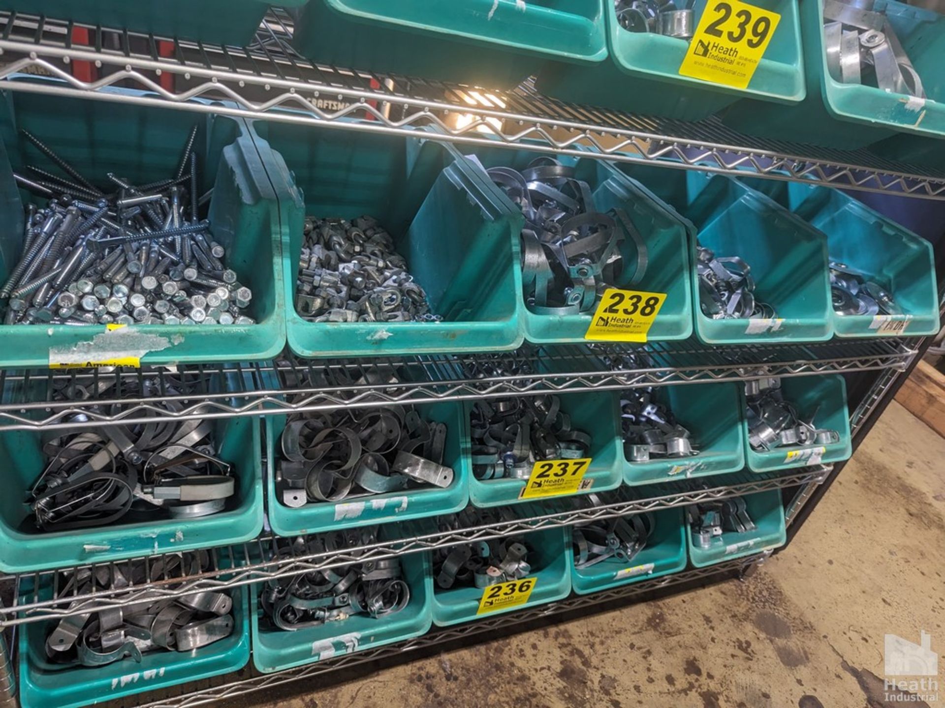 LARGE QUANTITY OF PIPE HANGERS AND LAG SCREWS ON SHELF (NO GREEN BINS, CONTENTS ONLY)