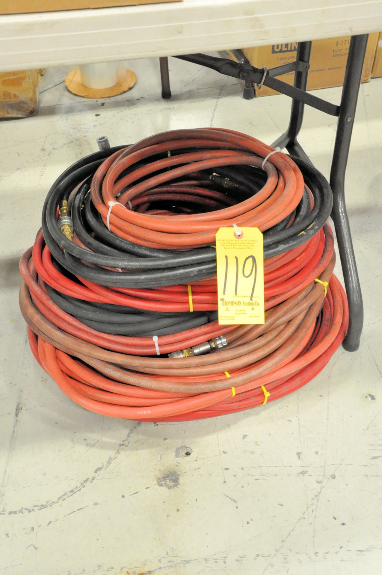 Lot-Long Air Hoses in (1) Stack on Floor Under (1) Table