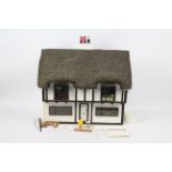 Dolls house - A home made, wooden, thatched, dolls house with electricity fittings for lights.