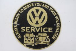 A cast iron wall plaque marked VW Service, approximately 24 cm (d).