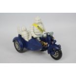 A cast iron model depicting Bibendum (Michelin Man) with a motorcycle and sidecar.