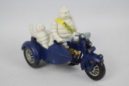 A cast iron model depicting Bibendum (Michelin Man) with a motorcycle and sidecar.