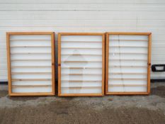 Three wooden wall mounted display cabinets.